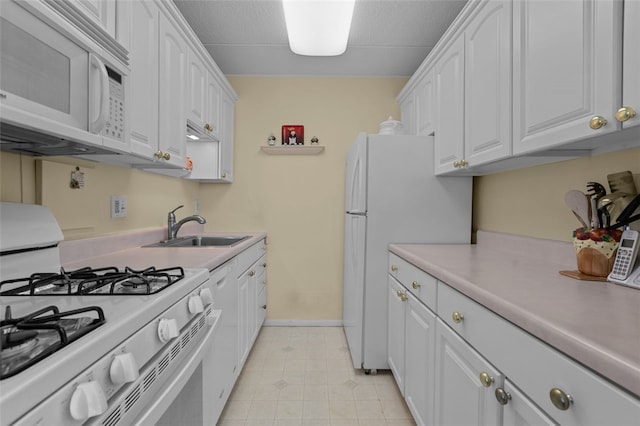 kitchen with white appliances, white cabinets, a sink, and light countertops