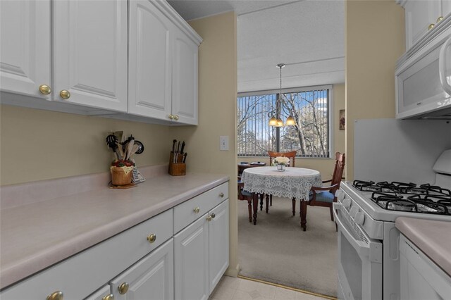 kitchen with a notable chandelier, light countertops, hanging light fixtures, white cabinets, and white appliances