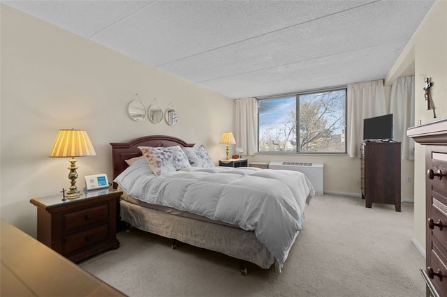 carpeted bedroom featuring radiator heating unit, baseboards, and a textured ceiling