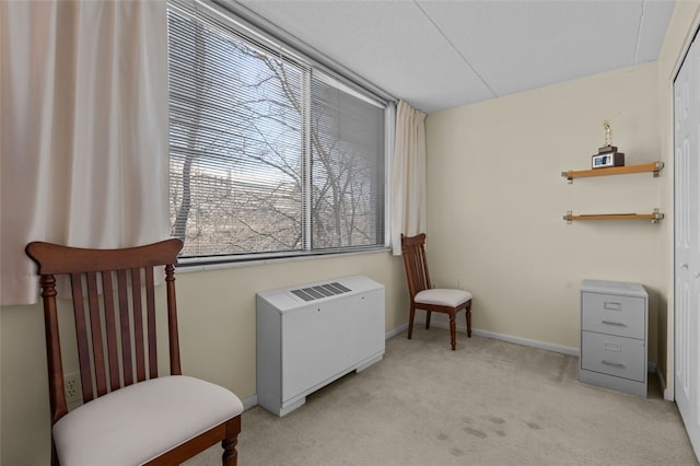 living area featuring baseboards, light colored carpet, and radiator heating unit