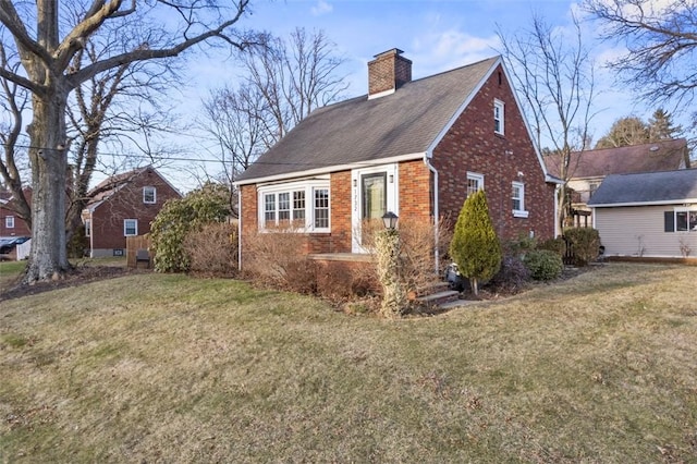 exterior space with brick siding, a yard, and a chimney