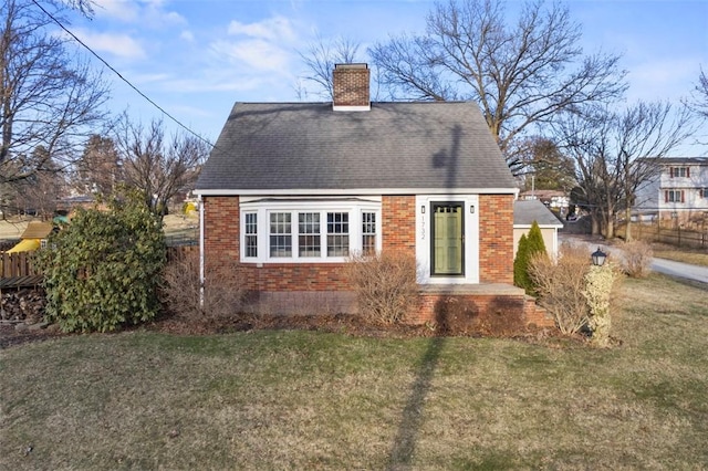 rear view of property with brick siding, a yard, a chimney, roof with shingles, and fence