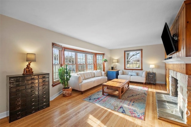 living area featuring a fireplace, baseboards, and wood finished floors