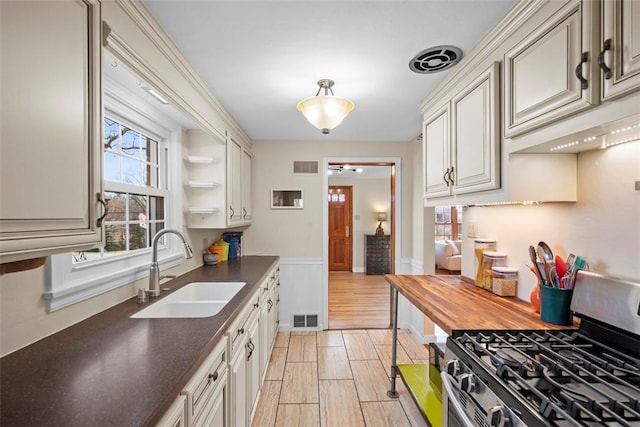 kitchen featuring dark countertops, visible vents, a sink, and gas stove