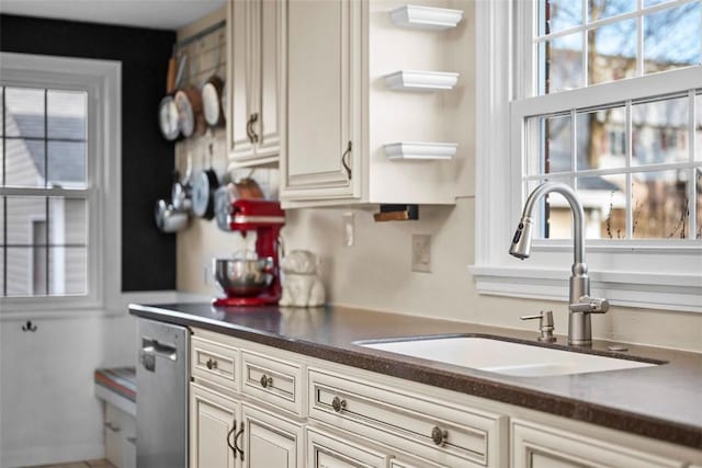 kitchen with dark countertops, stainless steel dishwasher, and a sink