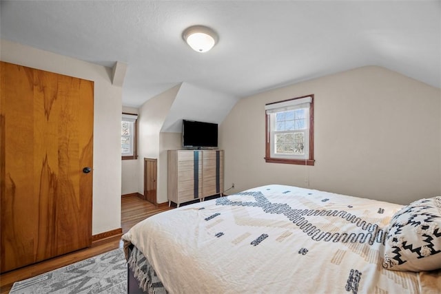 bedroom with lofted ceiling, baseboards, and wood finished floors