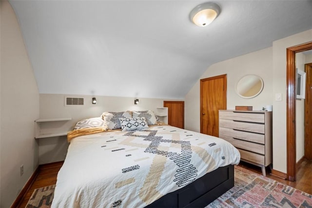 bedroom featuring lofted ceiling, wood finished floors, visible vents, and baseboards