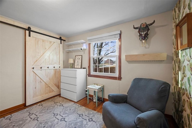 living area with light wood-style floors, baseboards, and a barn door