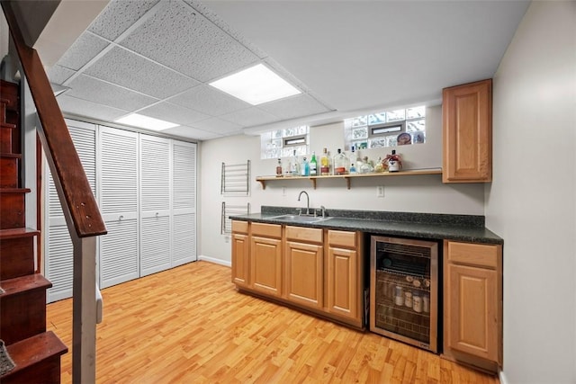 bar with beverage cooler, a sink, stairs, light wood-type flooring, and wet bar