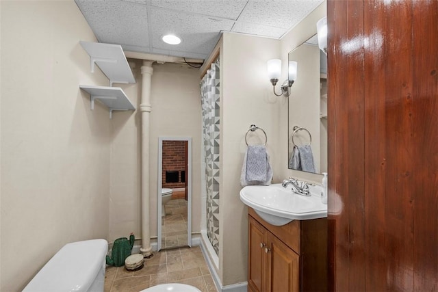 bathroom with a paneled ceiling, a stall shower, vanity, and toilet