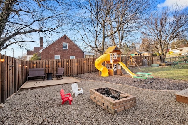 view of playground with an outdoor fire pit, a fenced backyard, and a deck