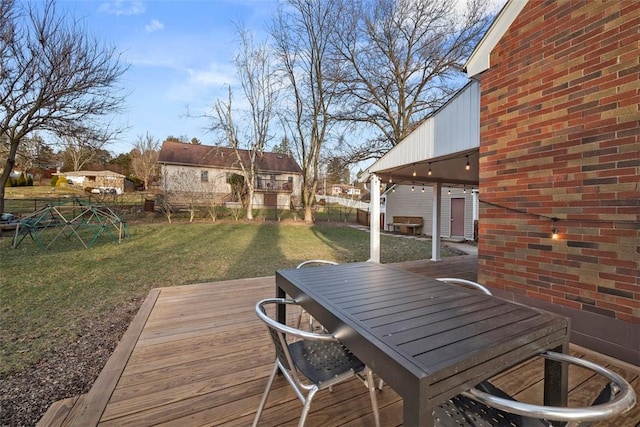 wooden deck with outdoor dining space, fence, and a yard