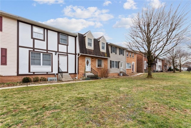 view of front facade featuring entry steps, brick siding, a residential view, and a front yard