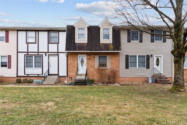 view of property with brick siding, a shingled roof, entry steps, cooling unit, and a front lawn