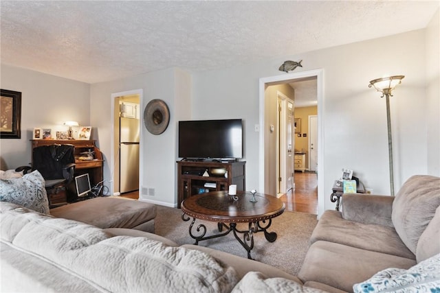 living room featuring a textured ceiling, visible vents, and baseboards