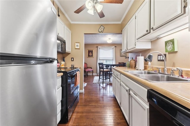 kitchen with dark wood-style flooring, crown molding, light countertops, a sink, and black appliances