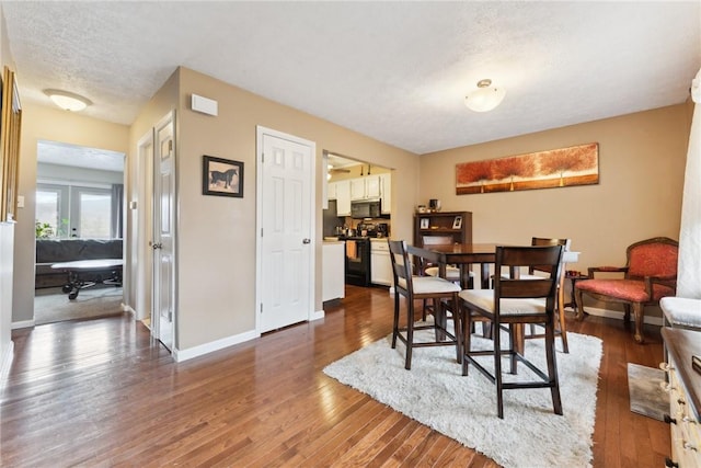 dining space with dark wood-type flooring, a textured ceiling, and baseboards