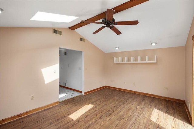 spare room with baseboards, vaulted ceiling with skylight, visible vents, and wood finished floors