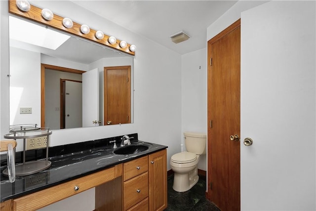 bathroom with a skylight, vanity, and toilet