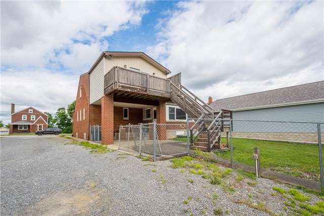 view of front facade featuring brick siding, fence, stairway, and a wooden deck