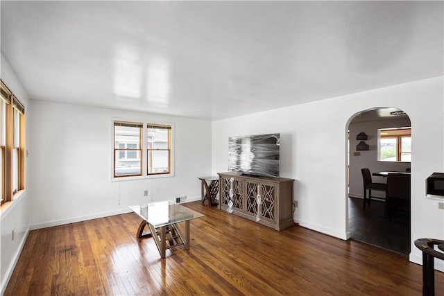 empty room featuring arched walkways, visible vents, hardwood / wood-style flooring, and baseboards