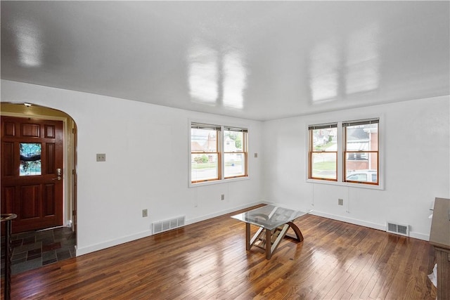 interior space with baseboards, visible vents, arched walkways, and hardwood / wood-style floors