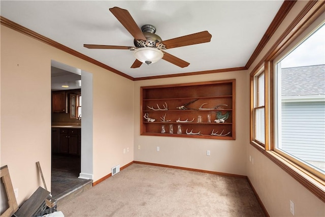 spare room with crown molding, visible vents, and baseboards