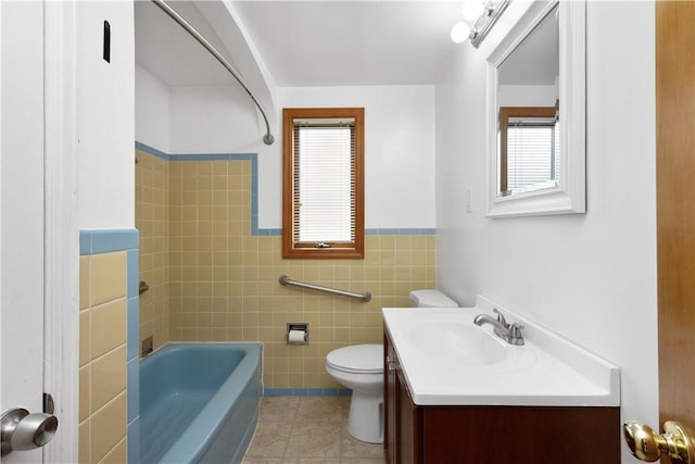 bathroom featuring bathtub / shower combination, tile patterned flooring, toilet, vanity, and tile walls