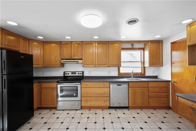 kitchen featuring under cabinet range hood, a sink, visible vents, appliances with stainless steel finishes, and dark countertops