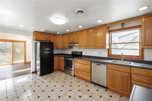 kitchen featuring visible vents, dark countertops, appliances with stainless steel finishes, under cabinet range hood, and a sink