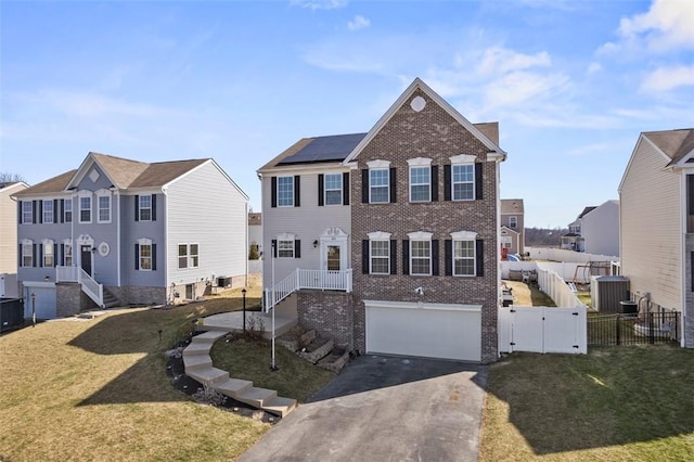 view of front of property featuring aphalt driveway, an attached garage, brick siding, fence, and a gate