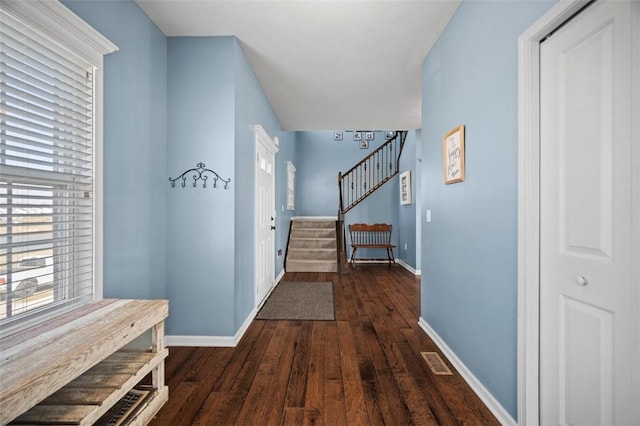 hall featuring stairs, dark wood-type flooring, visible vents, and baseboards