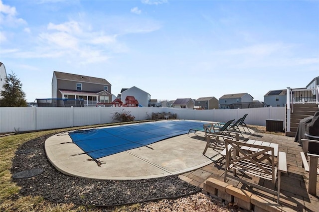 view of swimming pool featuring a fenced backyard, a residential view, a fenced in pool, and a patio