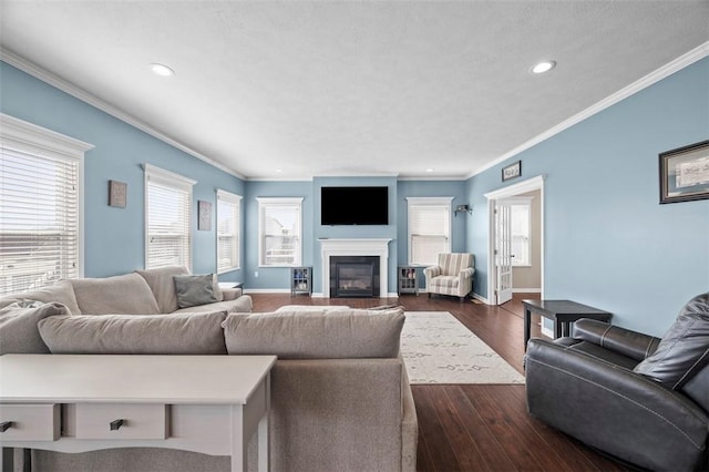 living room with ornamental molding, dark wood-style flooring, a glass covered fireplace, and baseboards