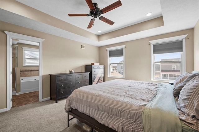 bedroom with carpet floors, a raised ceiling, visible vents, and baseboards