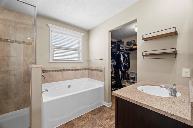 bathroom featuring a tile shower, a walk in closet, a bath, and vanity