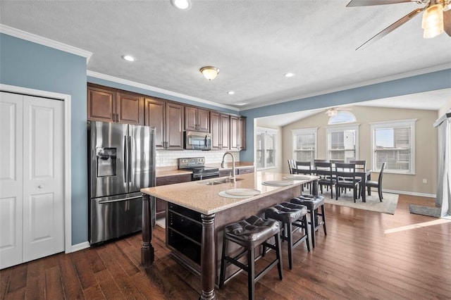 kitchen featuring dark wood finished floors, decorative backsplash, a breakfast bar, stainless steel appliances, and a sink