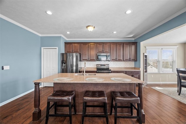 kitchen with stainless steel appliances, backsplash, a kitchen bar, and a sink