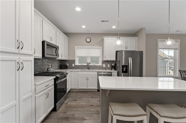 kitchen with stainless steel appliances, visible vents, white cabinets, decorative backsplash, and a kitchen bar