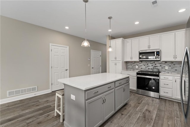 kitchen with visible vents, dark wood-type flooring, gray cabinets, stainless steel appliances, and backsplash