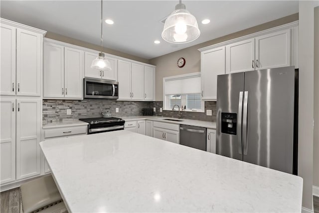 kitchen with stainless steel appliances, tasteful backsplash, a sink, and white cabinets