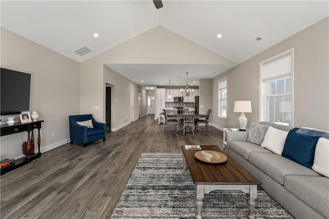 living room with lofted ceiling, visible vents, baseboards, dark wood-style floors, and an inviting chandelier