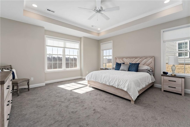 carpeted bedroom with ornamental molding, a tray ceiling, visible vents, and baseboards