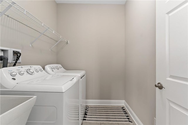 laundry room featuring a sink, laundry area, washing machine and clothes dryer, and baseboards