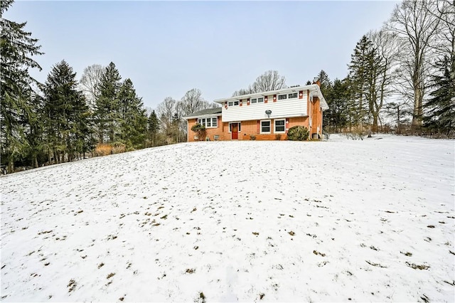 snow covered rear of property with brick siding