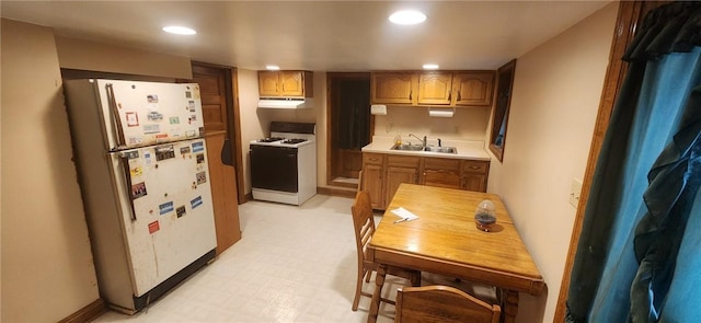 kitchen with recessed lighting, under cabinet range hood, white appliances, a sink, and light floors