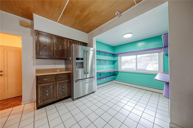 kitchen with light tile patterned floors, wooden ceiling, light countertops, dark brown cabinets, and stainless steel refrigerator with ice dispenser