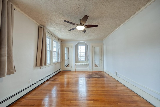 empty room featuring a baseboard radiator, ornamental molding, ceiling fan, a textured ceiling, and hardwood / wood-style floors