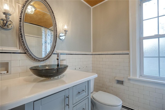 bathroom with crown molding, tile walls, toilet, a baseboard heating unit, and vanity