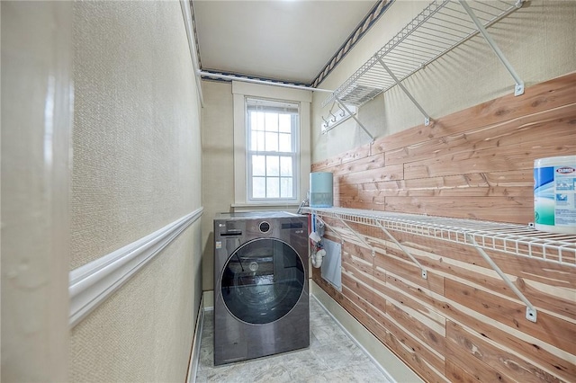 laundry area featuring a textured wall, laundry area, washer / clothes dryer, and wood walls